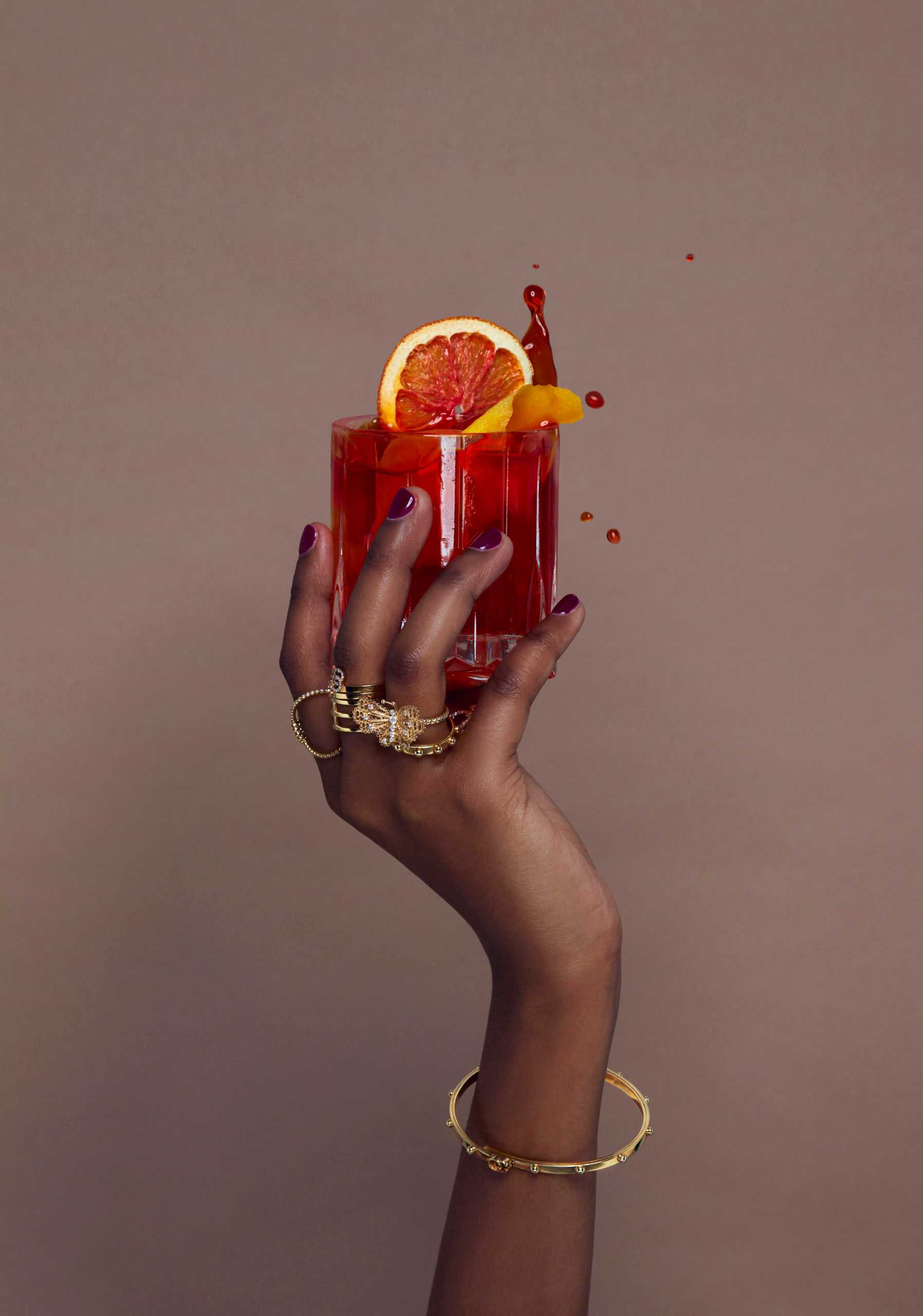 blood orange cocktail in hand with jewlery